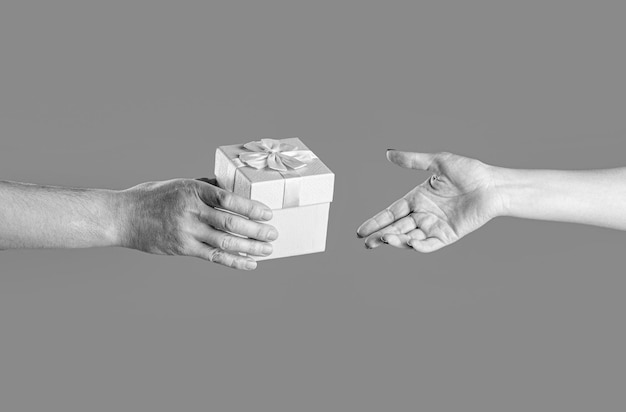Menina dá um presente ao homem Mulher mãos segurando presente caixa de presente na mão surpresa e conceito de feriado preto e branco