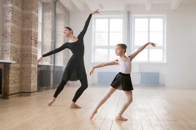 Menina dançando balançando junto com seu treinador durante as aulas no estúdio de dança