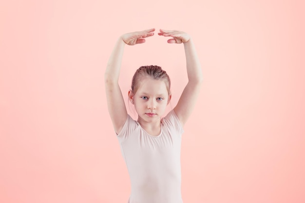 Menina dançarina de balé em tutu posando com braços levantados sobre fundo rosa fotografia de stock