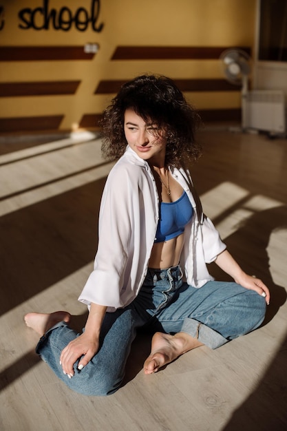 Menina dançarina em roupas casuais dançando dança contemporânea dentro do salão nas luzes do sol da manhã