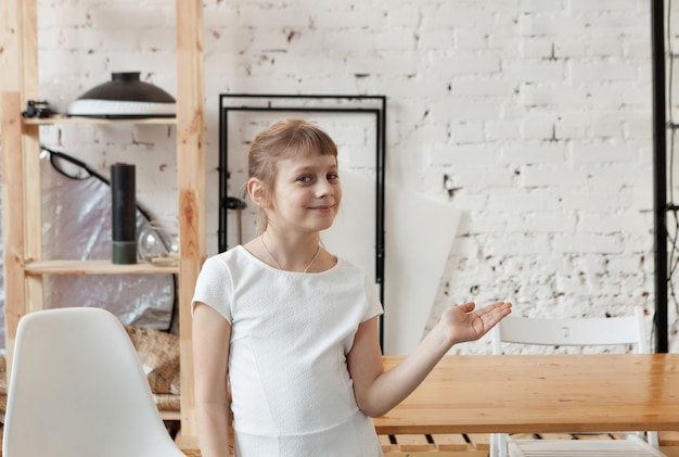 Menina de 8 anos com vestido branco apontando a mão para o lado