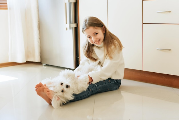 Menina de 9 anos com modelo de cabelo comprido com um cão de estimação estudante maltesa em casa estilo de vida