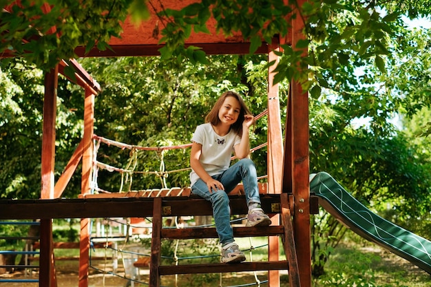 Menina de 9 anos ri alegremente faz caretas faz caretas nas brincadeiras de estilo de vida do playground