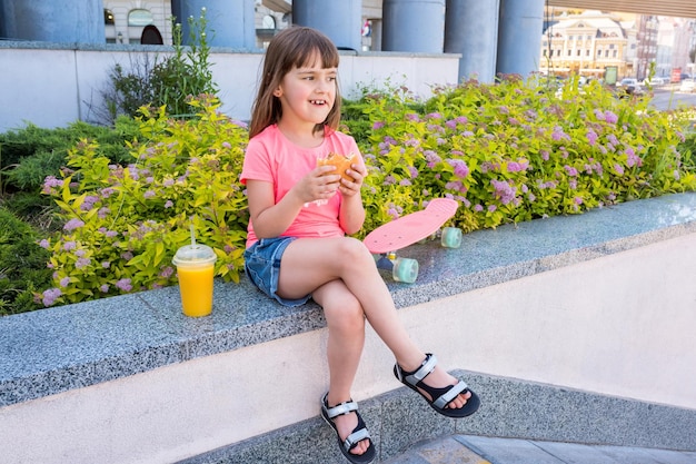 Menina de anos comendo um hambúrguer na rua fast-food