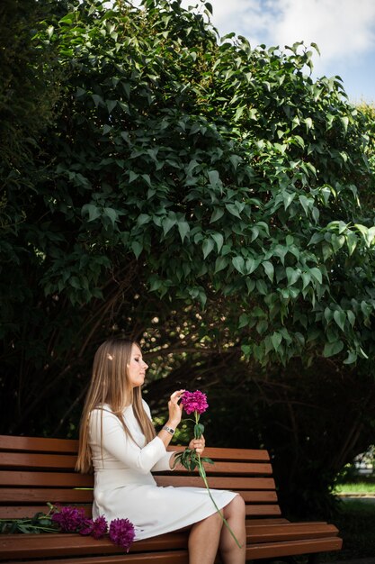 Menina de aparência européia com flores, peônias em suas mãos