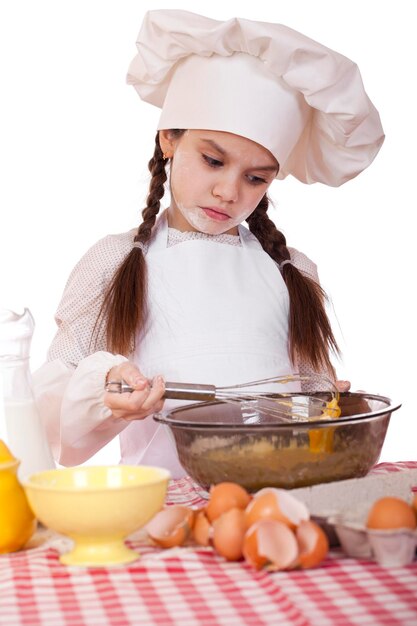Foto menina de avental branco quebra perto do prato com ovos isolados em fundo branco