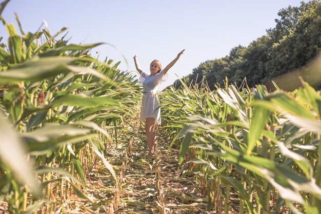 Foto menina de beleza no campo de milho de verão, céu azul claro. mulher jovem e feliz saudável curtindo a natureza ao ar livre. correndo e girando feminino. vôo. livre, conceito de liberdade, meio ambiente