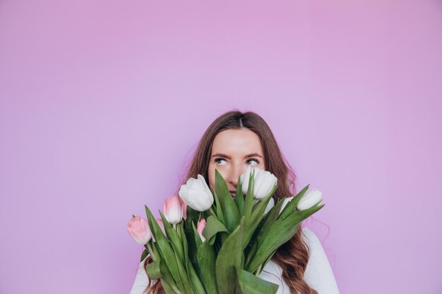 Menina de beleza segurando o buquê de flores de tulipas de primavera e sorrindo. Dia dos Namorados. Dia das Mães.