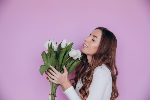 Menina de beleza segurando o buquê de flores de tulipas de primavera e sorrindo. Dia dos Namorados. Dia das Mães.