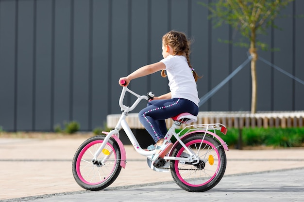 Menina de bicicleta no parque de verão andando de bicicleta ao ar livre