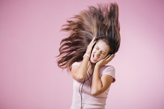 Menina de cabelo castanho com auscultadores a ouvir música com os olhos fechados