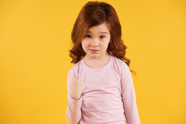 Menina de cabelo vermelha que ameaça, mostrando o punho.