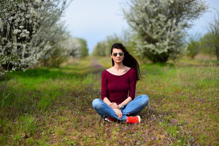 Foto menina de cabelos castanhos em óculos de sol, sentado no prado flor