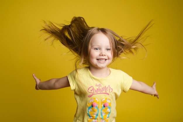 Menina de cabelos comprida em camisa bonitinha brincando com cabelo e girando