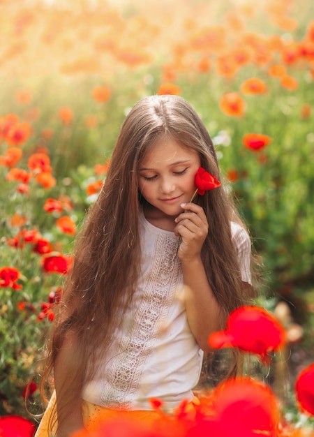 Menina de cabelos compridos posando no campo de papoulas com sol de verão vertical