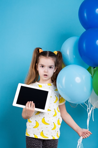 Menina de cabelos escuros com balões e tablet