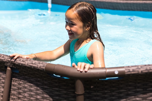 Menina de cabelos loiros em uma piscina desfrutando na água Piscina maiô crianças verão relaxar resort de férias e conceito de viagem