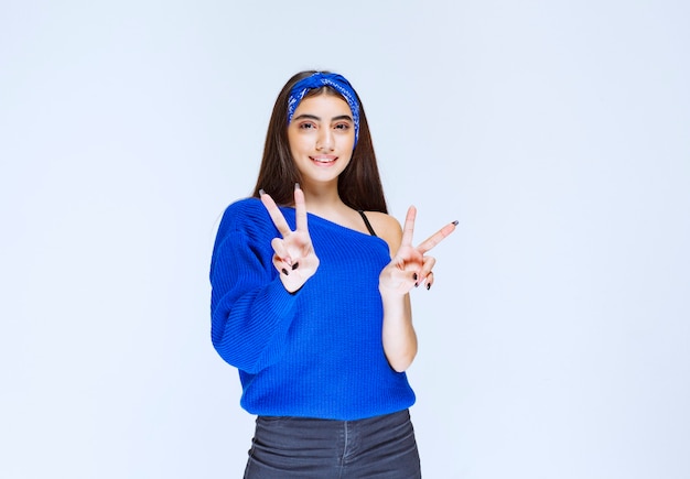 Menina de camisa azul, mostrando o símbolo da paz.