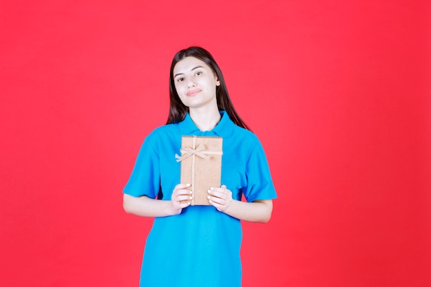 Menina de camisa azul segurando uma mini caixa de presente de papelão