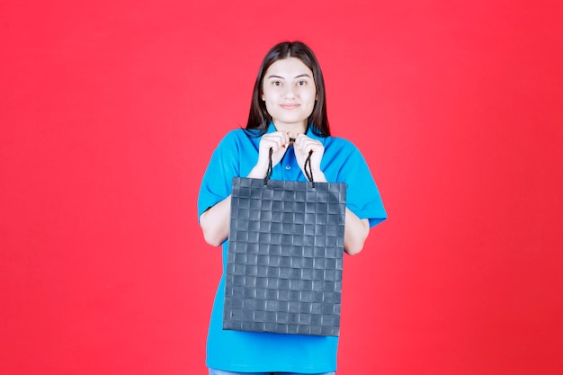 Menina de camisa azul segurando uma sacola roxa