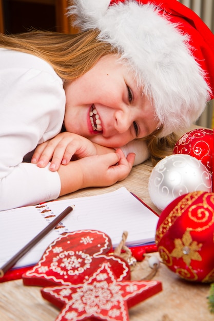 Menina de chapéu de natal escrever carta ao papai noel