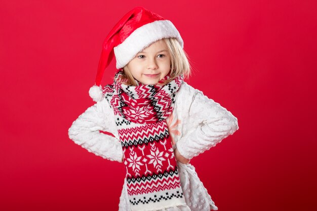 Menina de chapéu de Papai Noel e cachecol no vermelho