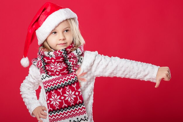 Menina de chapéu de Papai Noel e cachecol no vermelho