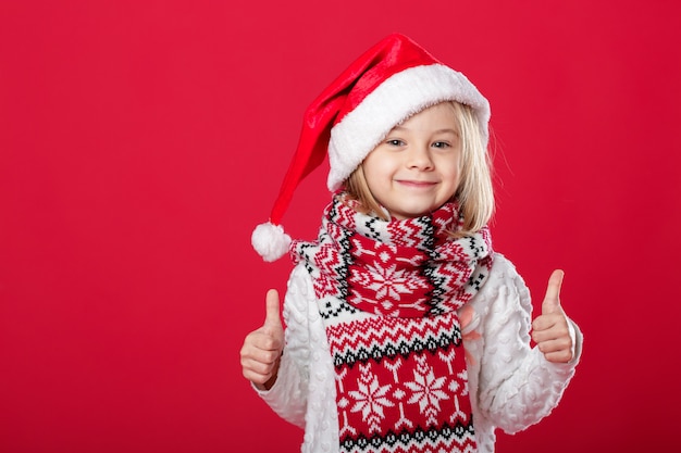 Menina de chapéu de Papai Noel e cachecol no vermelho