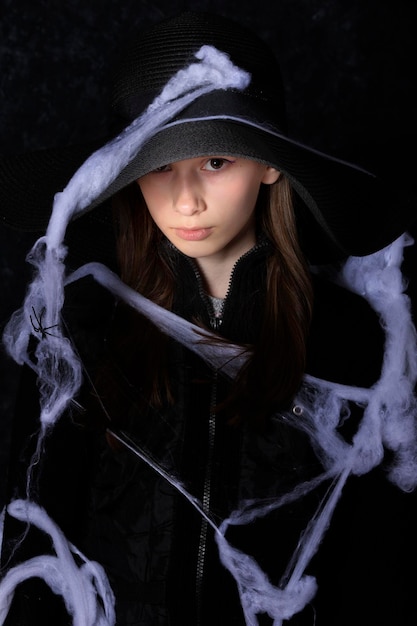 Foto menina de chapéu preto em uma teia de aranha de halloween