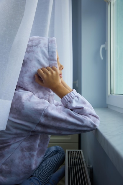 Menina de chapéu sentado e se aquecendo na bateria