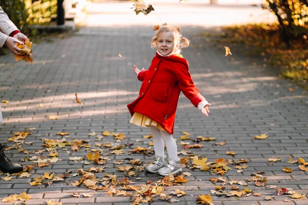 Menina de comprimento com folhas de outono na calçada