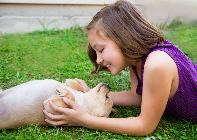 menina de crianças brincando com cachorro chihuahua deitado no gramado