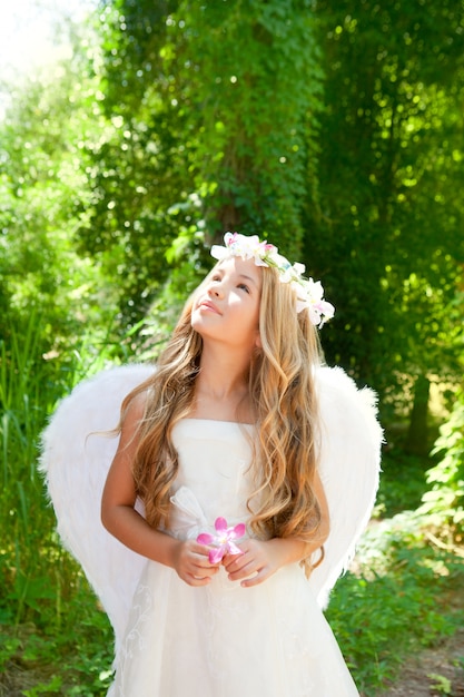 Menina de crianças de anjo segurando flor na mão, olhando o céu