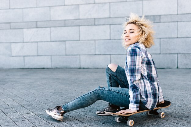 Foto menina de esportes atraente sentada em um skate