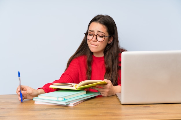 Menina de estudante adolescente frustrada estudando em uma tabela