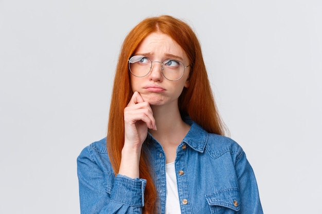 Menina de faculdade ruiva tímida bonito mal-humorado inquieto em copos, procure pensativo e sonhador