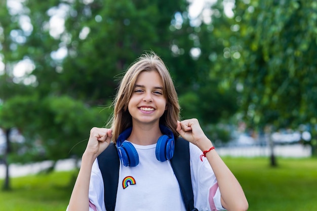 Foto menina de idade adolescente com mochila e fone de ouvido no parque de volta ao conceito de escola