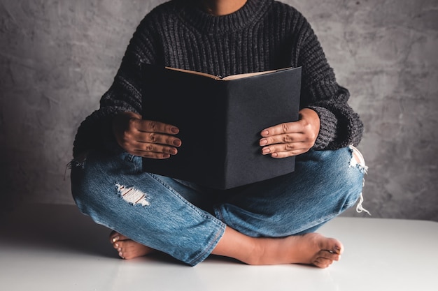 Menina de jeans em cima da mesa lê livros. Educação, Desenvolvimento