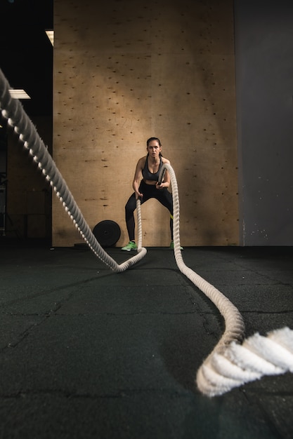 Menina de luta de cordas no ginásio treino exercício equipado corpo