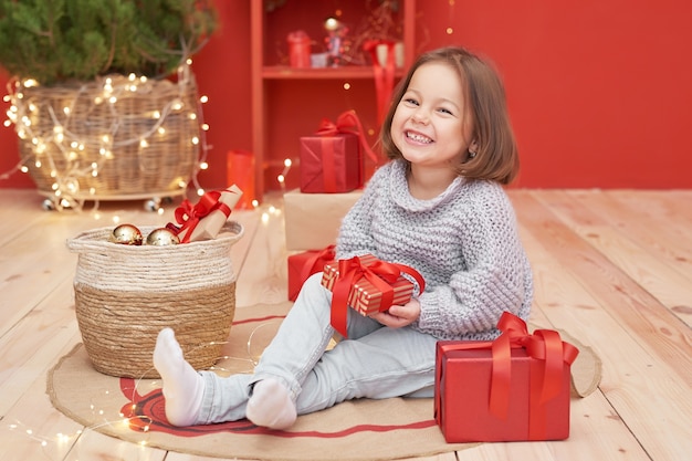 Menina de Natal com presentes perto da árvore de Natal