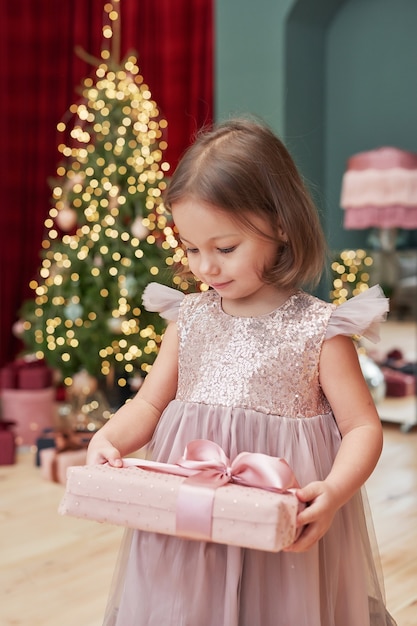 Menina de Natal com presentes perto da árvore de Natal