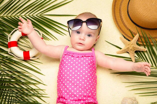 Menina de óculos de sol com acessórios de praia. Férias no mar com bebê, conceito de verão