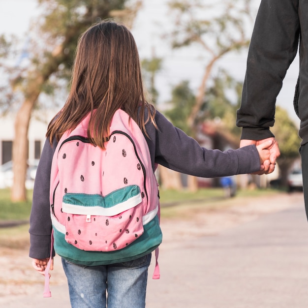 Menina de pai andando de colheita para a escola