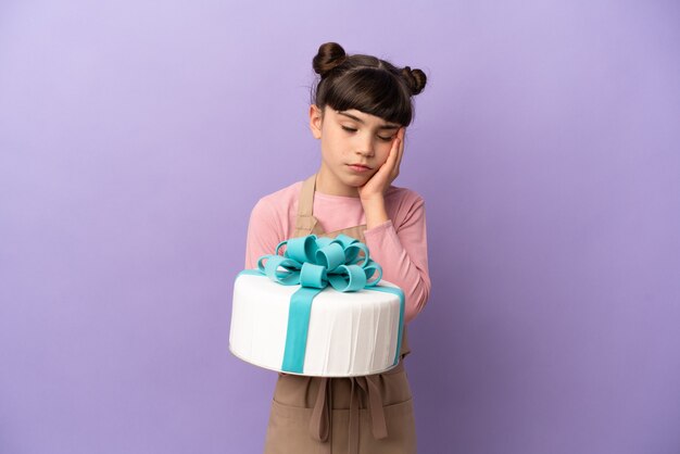 Menina de pastelaria segurando um grande bolo isolado em um fundo roxo com dor de cabeça
