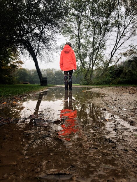 Foto menina de pé na poça contra as árvores