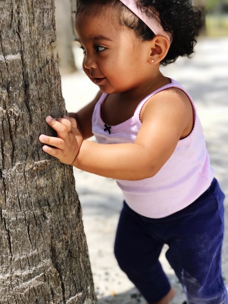 Foto menina de pé perto de uma árvore