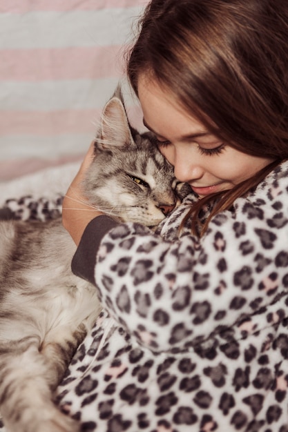 Menina de pijama abraçando o gato