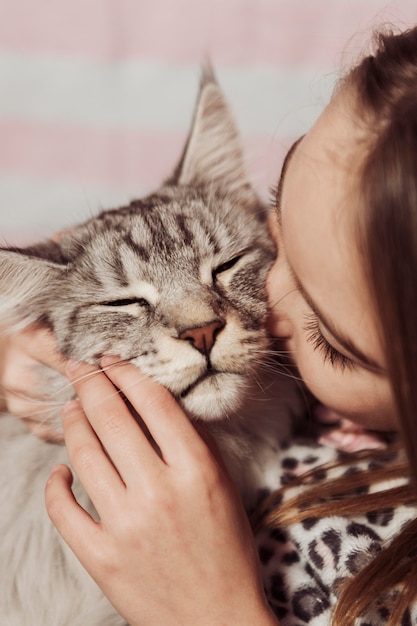 Foto menina de pijama beijando o gato