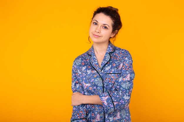 Menina de pijama posando enquanto descansava em casa sobre fundo amarelo