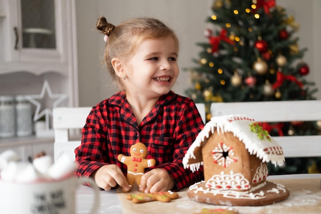 menina de pijama vermelho segurando biscoito de gengibre de natal decorado para homens